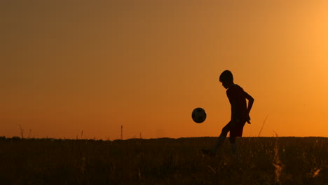 Silueta-De-Un-Niño-Jugando-Al-Fútbol-Al-Atardecer.-Un-Niño-Hace-Malabarismos-Con-Una-Pelota-En-El-Campo-Al-Atardecer.